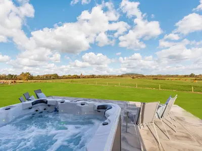 a hot tub on a patio with chairs at Buckley Farm, Barn 1 - Uk36588 in Oswestry