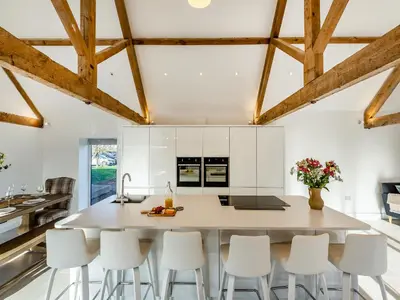 a kitchen with white cabinets and a large island with white stools at Buckley Farm, Barn 1 - Uk36588 in Oswestry