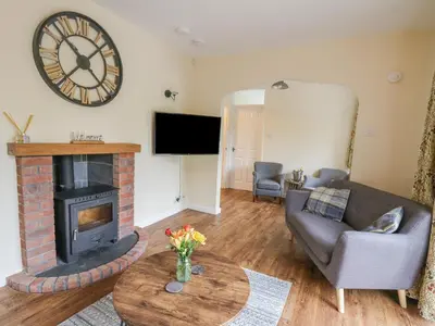 a living room with a fireplace and a clock on the wall at Ger Yr Afon Cottage in Rhayader