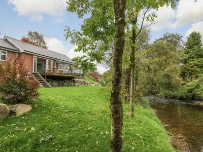 a house with a river in front of it at Ger Yr Afon Cottage in Rhayader