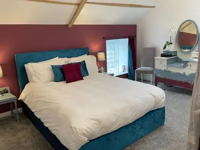a bedroom with a large bed with a blue headboard at The Good Life Wales with Hot tubs in Llywel