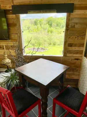 a table and two chairs in a room with a window at The Good Life Wales with Hot tubs in Llywel