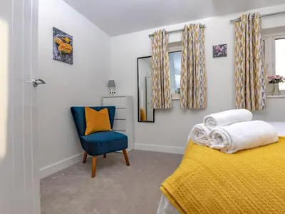 a bedroom with a yellow bed and a blue chair at 2 Bedroom Home Near the Heart of Ludlow - Pass the Keys in Ludlow