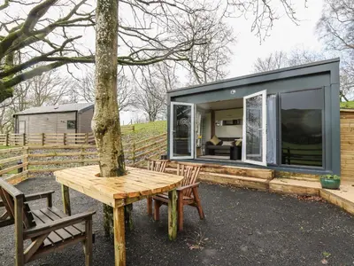 a small house with a table and a tree at The Fox Den in Rhayader