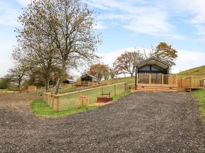 a cabin in a field with a fence at Meadow Retreat in Rhayader