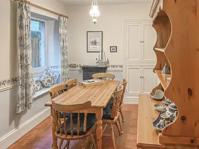a dining room with a wooden table and chairs at New Cottage in Penmaenpool