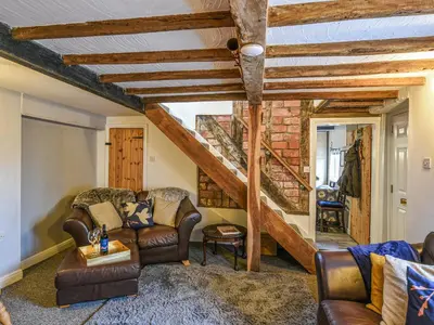 a living room with leather furniture and a staircase at Bodeinion in Llanfair Caereinion