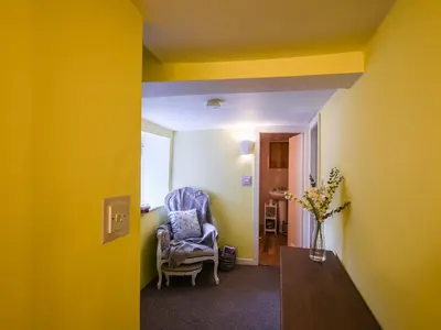 a room with yellow walls and a chair and a table at Glasfor in Llwyngwril