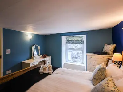 a bedroom with blue walls and a bed and a window at Glasfor in Llwyngwril