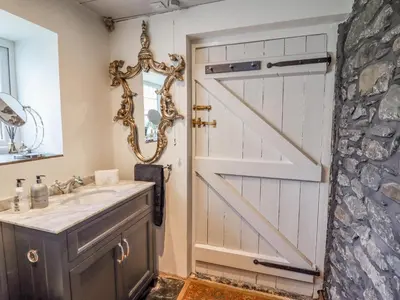 a bathroom with a barn door and a sink at Neuadd Wen in Derwen