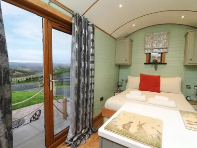a bedroom with a bed and a balcony at Highland View in Rhayader