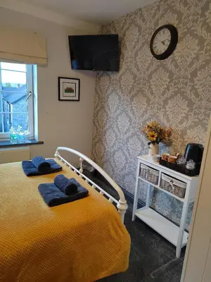 a bedroom with a bed and a clock on the wall at Rooms by the River at Glan Aber in Cynwyd