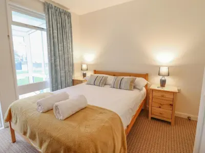 a bedroom with a large bed and a window at 48 Glan Y Mor in Fairbourne