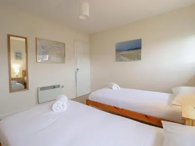 two beds in a room with white walls at 48 Glan Y Mor in Fairbourne