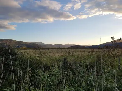 a field of grass with the sunset in the background at 48 Glan Y Mor in Fairbourne