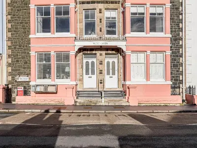 a pink building with a white door on a street at Apartment 1 - Uk32244 in Aberdyfi