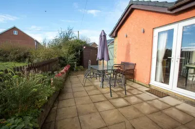 a patio with a table and chairs and an umbrella at Goitre Bach Cottage in Aberaeron