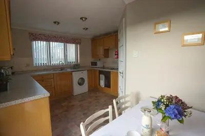a kitchen with a table with a vase of flowers on it at Goitre Bach Cottage in Aberaeron