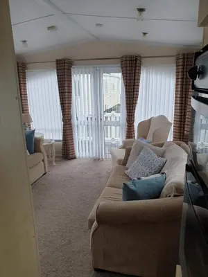 a living room with a couch and chairs and windows at Barmouth Lyons Sunnysands 346 in Talybont
