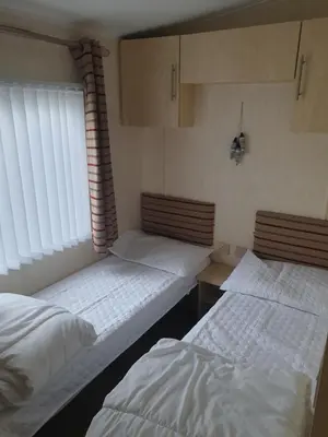 two twin beds in a room with a window at Barmouth Lyons Sunnysands 346 in Talybont