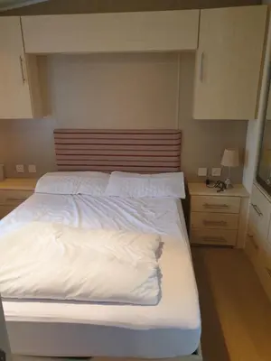 a bedroom with a large bed with white sheets at Barmouth Lyons Sunnysands 346 in Talybont