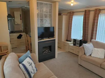 a living room with a tv and a couch and a fireplace at Barmouth Lyons Sunnysands 346 in Talybont