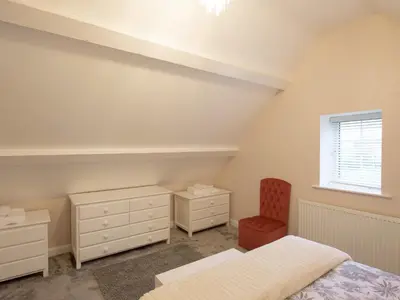 a bedroom with a bed and a dresser and a window at The Coach House in Oswestry
