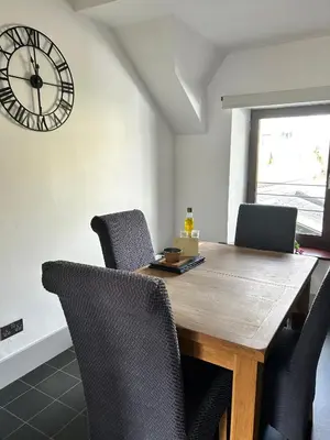 a dining room table with chairs and a clock on the wall at Cadwgan House in Rhayader
