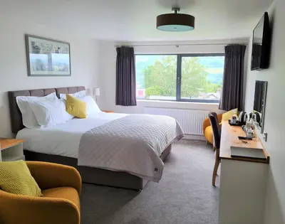 a bedroom with a bed and a desk and a window at Camden Lodge B&B and Cottage Brecon in Brecon