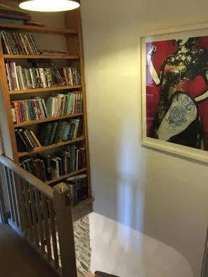 a room with a staircase and a book shelf filled with books at Chapel Cottage in Machynlleth