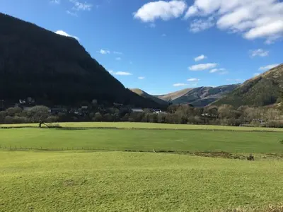 a large green field with mountains in the background at Chapel Cottage in Machynlleth