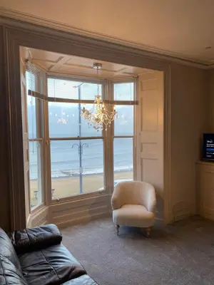 a living room with a chair and a large window at Lan Y Môr 4 Aberystwyth in Aberystwyth