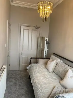 a bedroom with a large bed and a chandelier at Lan Y Môr 4 Aberystwyth in Aberystwyth