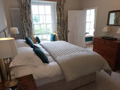 a large white bed in a bedroom with windows at Baskerville House in Clyro