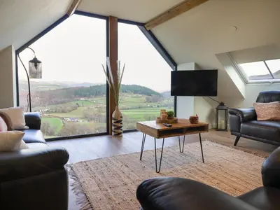 a living room with a couch and a table at Tyn Llwyn Barn in Corwen