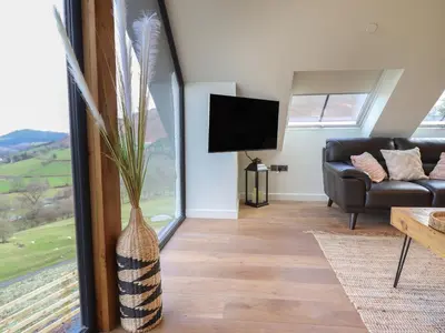 a living room with a couch and a tv at Tyn Llwyn Barn in Corwen