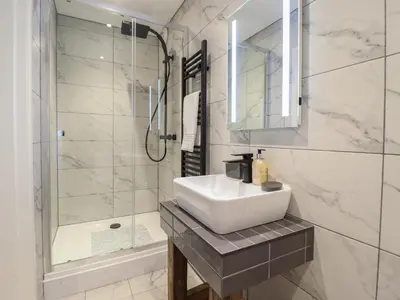 a white bathroom with a sink and a shower at Tyn Llwyn Barn in Corwen