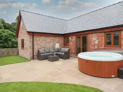 a patio with a hot tub in front of a house at The Clockhouse in Llandyssil