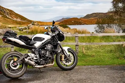 a motorcycle parked next to a fence next to a lake at Panoramic Mountain Retreat - Waen Fechan - 4x4 access only in Dolgellau