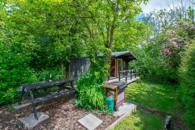 a small cabin with a bench and a tree at 4 Bed in New Quay oc-bow272 in New Quay