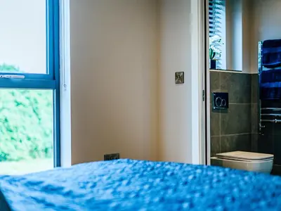 a bedroom with a blue bed and a window at Coed Y Pentre in Carno