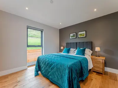 a bedroom with a bed with a blue comforter and a window at Coed Y Pentre in Carno