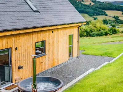 a building with a hot tub next to a house at Coed Y Pentre in Carno