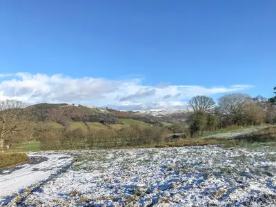 a snow covered road with a mountain in the background at Coed Y Pentre in Carno