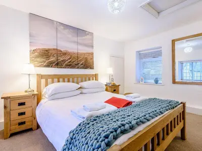a bedroom with a large bed and a painting on the wall at Pebble Cottage in Aberdyfi