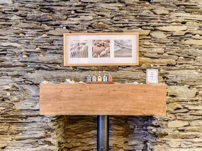 a picture on top of a table in front of a stone wall at Pebble Cottage in Aberdyfi