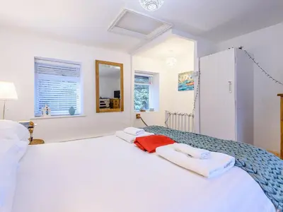 a bedroom with a white bed with towels on it at Pebble Cottage in Aberdyfi