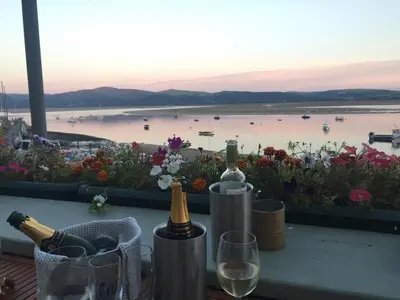 a table with wine bottles and glasses and a view of a harbor at Pebble Cottage in Aberdyfi
