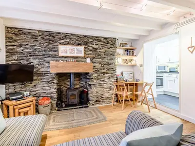 a living room with a stone wall with a fireplace at Pebble Cottage in Aberdyfi