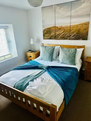 a bedroom with a large bed with blue and white sheets at Pebble Cottage in Aberdyfi